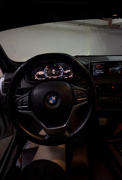 BMW digital instrument cluster installed in the cockpit with steering wheel and factory infotainment display