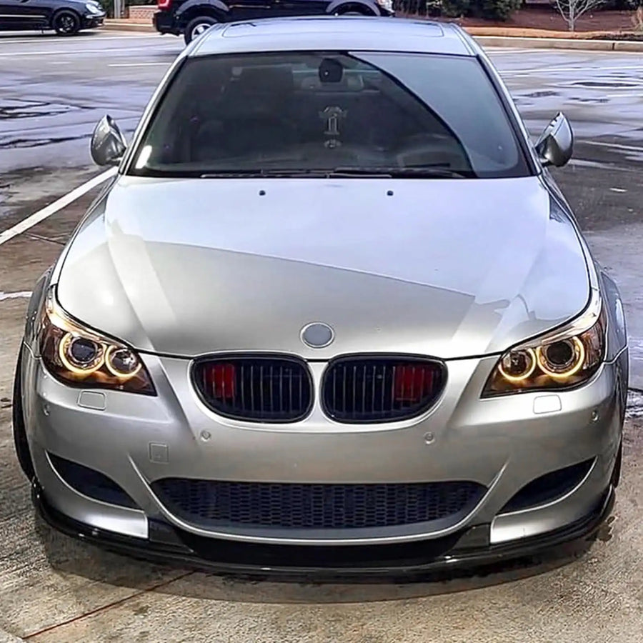 Silver BMW e60 car parked on a street with the headlights on