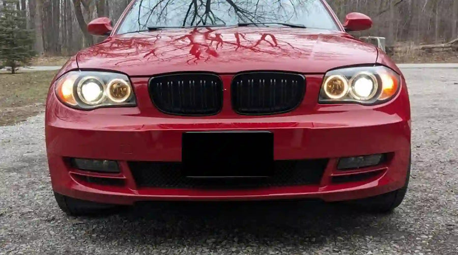 A bmw e82 shown from the front with the headlights on.