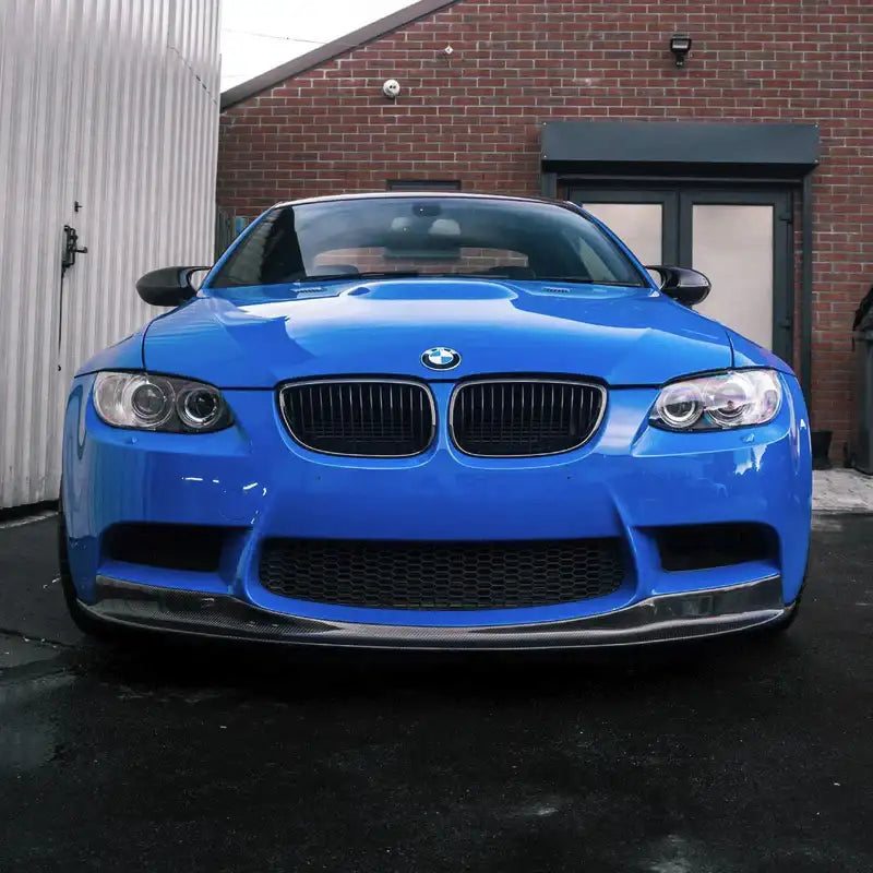 Blue BMW e92 car parked in front of a brick building