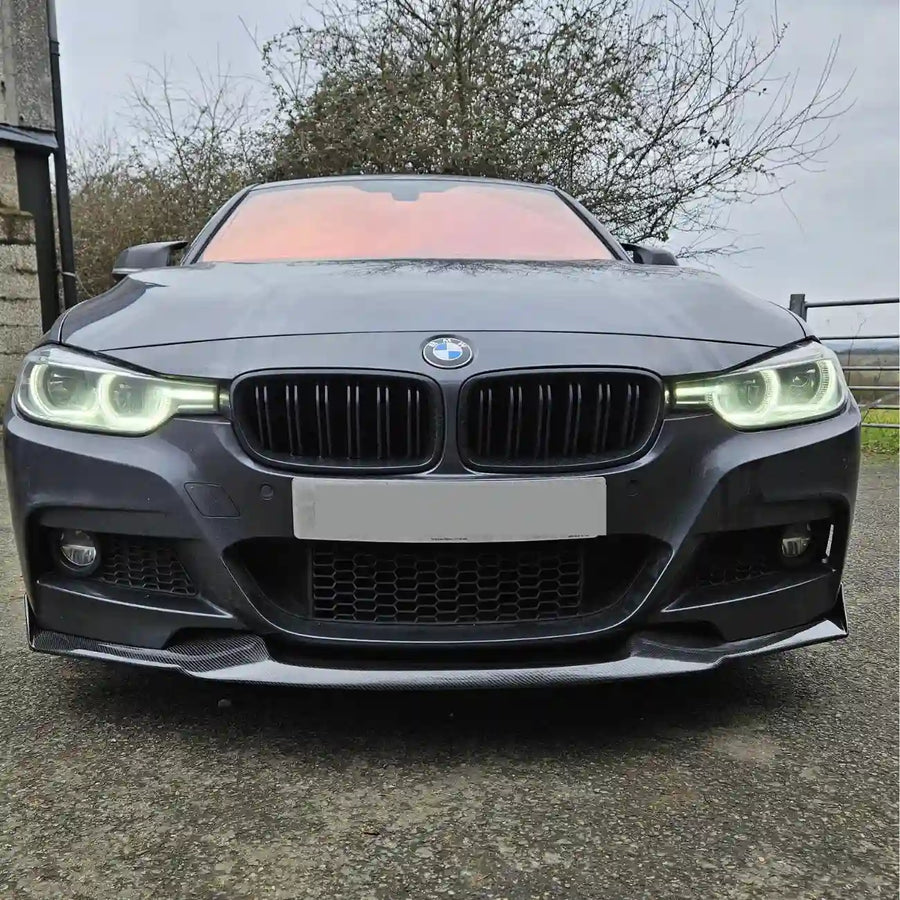Front view of a BMW f30 car on a road with trees in the background