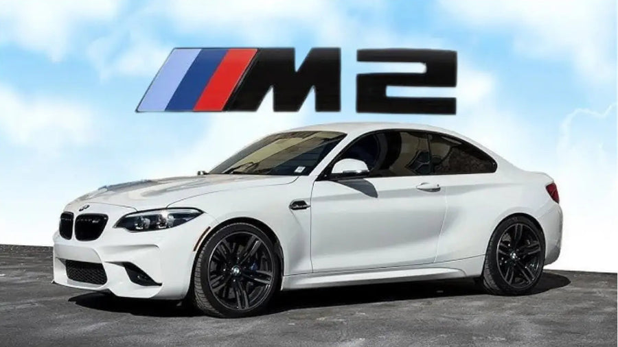 A white BMW M2 coupe shown from a three-quarter front angle, with a large BMW M2 logo graphic above it against a light blue cloudy sky background.