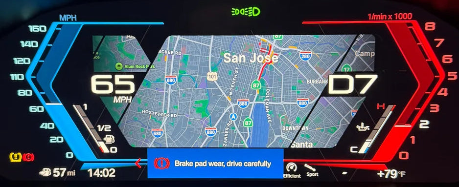 A close-up of a bmw digital instrument cluster display on a car dashboard, showing a navigation map, speed of 65 mph, and tachometer readings, illuminated with blue and red accents in a dark setting.