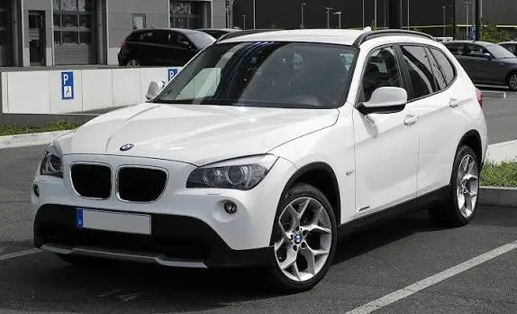 White BMW SUV E84 X1 parked on a street with a building in the background