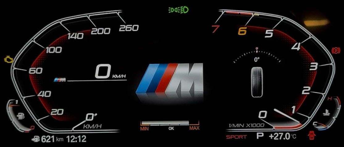 A bmw digital instrument cluster display on a car dashboard, showing illuminated speed and tachograph gauges with red, white, and black markings, plus an M logo in the center on a black background.