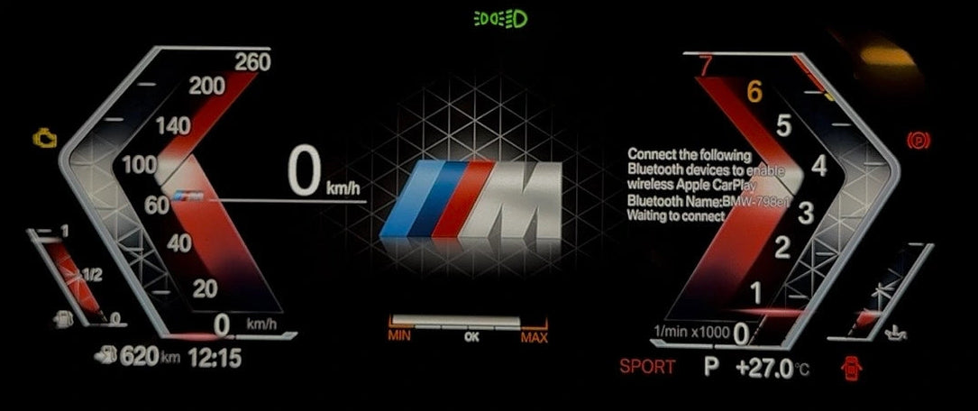 A close-up of a digital BMW instrument cluster display showing a speedometer, tachometer, and central BMW M logo on a dark dashboard.